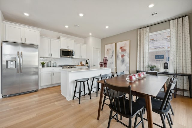 dining space with sink and light wood-type flooring