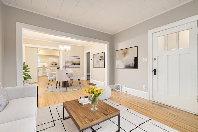 living room featuring an inviting chandelier, hardwood / wood-style flooring, and crown molding