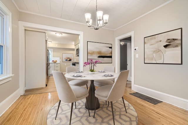 dining space with ornamental molding, light hardwood / wood-style floors, and a chandelier