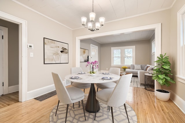 dining area featuring light hardwood / wood-style flooring, crown molding, and a chandelier