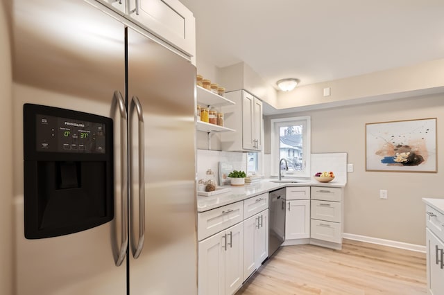 kitchen with stainless steel appliances, decorative backsplash, sink, light hardwood / wood-style flooring, and white cabinetry