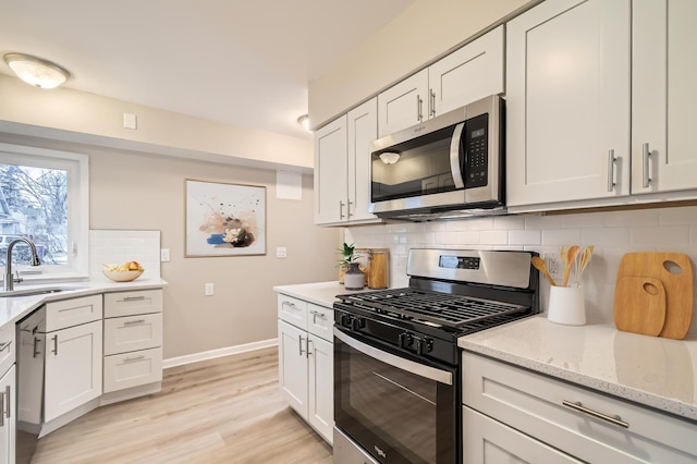 kitchen with sink, white cabinets, backsplash, and appliances with stainless steel finishes