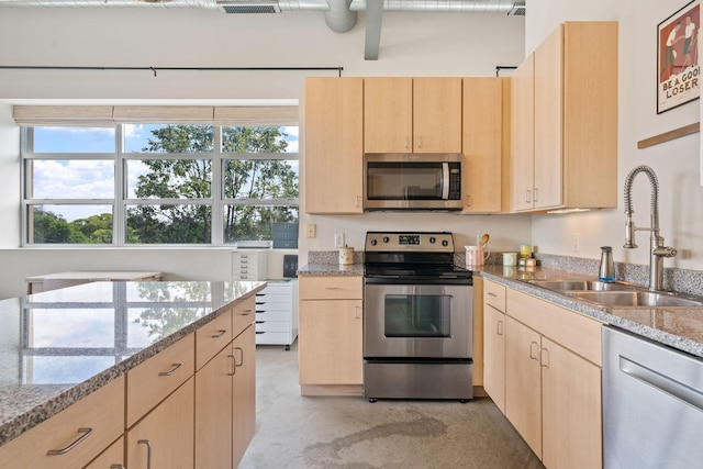 kitchen featuring light stone countertops, light brown cabinetry, sink, and appliances with stainless steel finishes