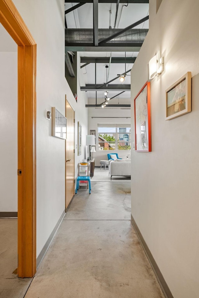 hallway featuring concrete flooring and a high ceiling