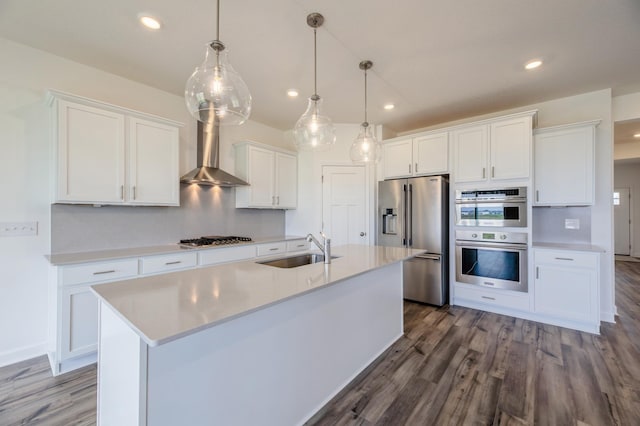 kitchen with stainless steel appliances, wall chimney range hood, sink, pendant lighting, and white cabinetry