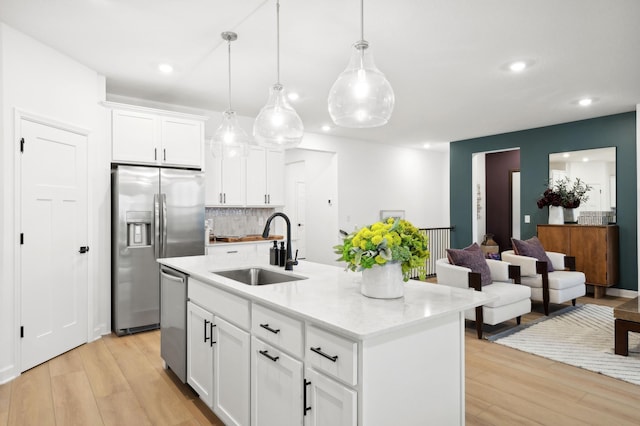 kitchen featuring sink, pendant lighting, a center island with sink, white cabinets, and appliances with stainless steel finishes