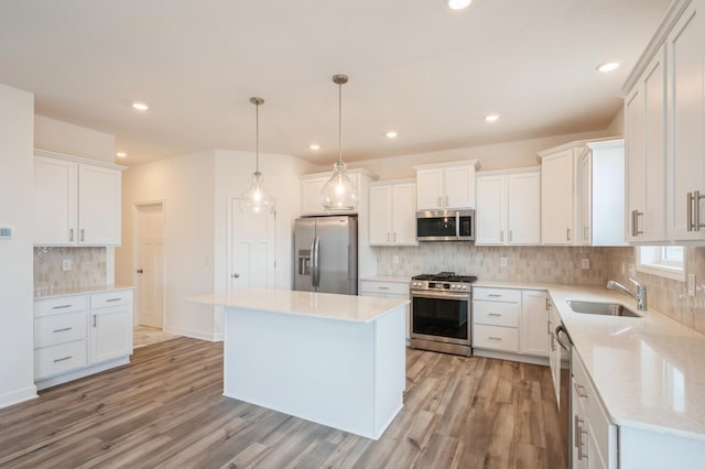 kitchen with a center island, white cabinets, sink, decorative light fixtures, and stainless steel appliances