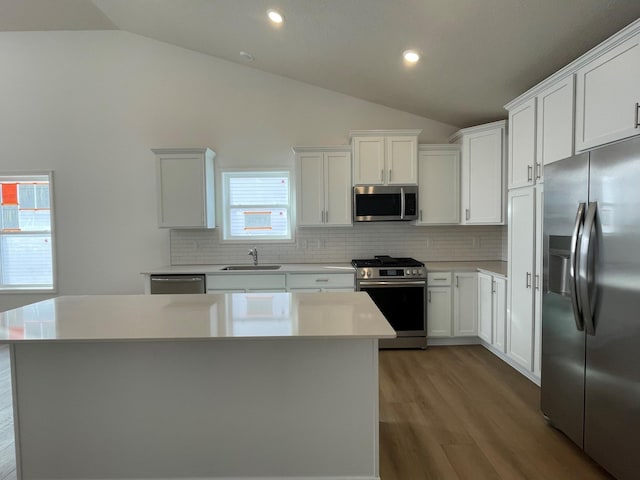 kitchen featuring white cabinetry, a center island, stainless steel appliances, and vaulted ceiling