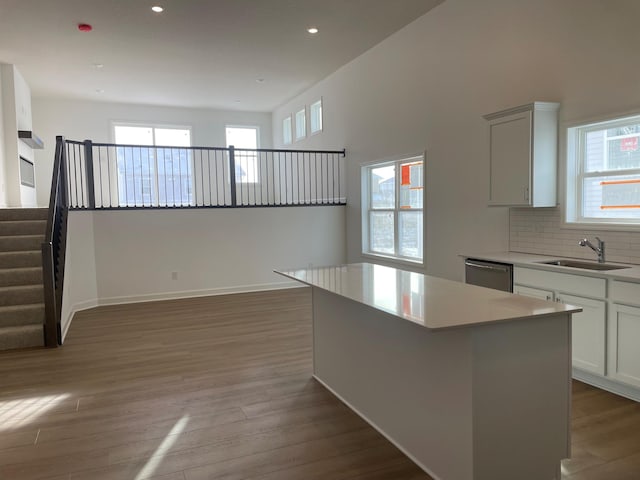 kitchen featuring a center island, stainless steel dishwasher, decorative backsplash, sink, and white cabinets