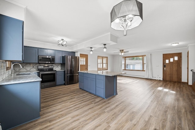 kitchen featuring sink, crown molding, a center island, stainless steel appliances, and light stone countertops