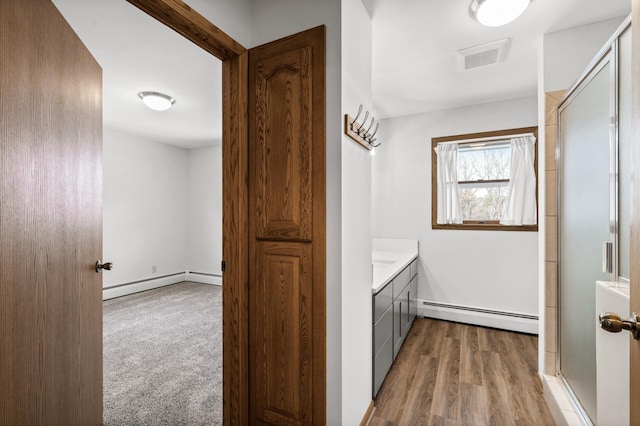 hall with a baseboard heating unit and light hardwood / wood-style flooring