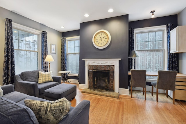 living room with light wood-type flooring, a wealth of natural light, and a brick fireplace