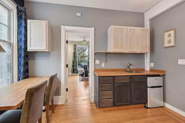 kitchen featuring dark brown cabinetry, light hardwood / wood-style floors, butcher block countertops, and sink