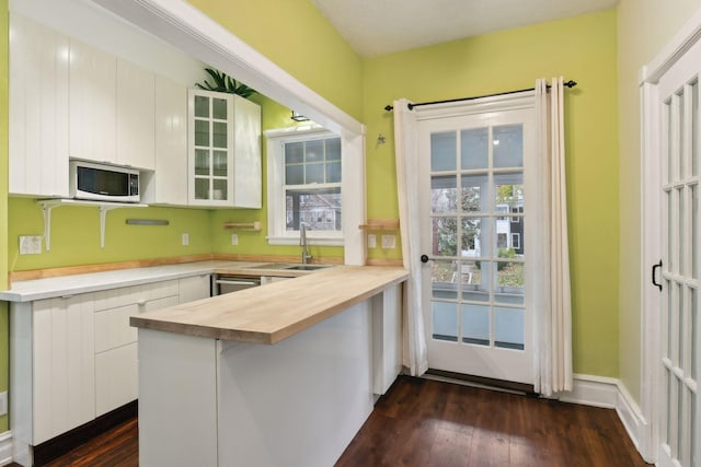 kitchen with a breakfast bar area, kitchen peninsula, dark hardwood / wood-style flooring, and white cabinets