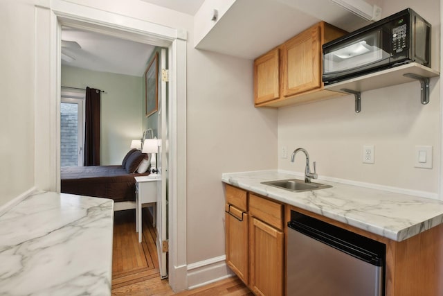 kitchen with light stone counters, sink, stainless steel dishwasher, and light wood-type flooring