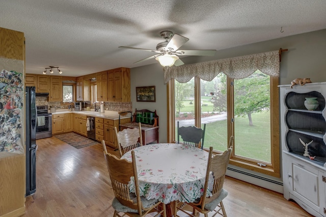 dining room with light wood-type flooring, a ceiling fan, a baseboard heating unit, and a textured ceiling