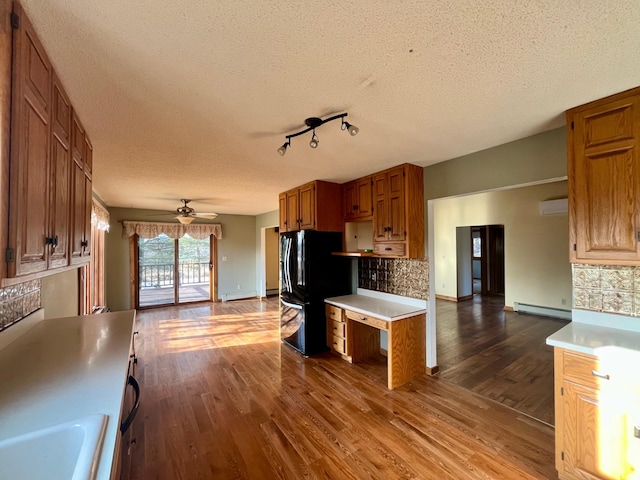 kitchen with a baseboard radiator, dark wood-style flooring, light countertops, freestanding refrigerator, and brown cabinets