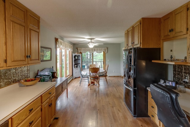 kitchen featuring light wood finished floors, brown cabinets, light countertops, a textured ceiling, and backsplash