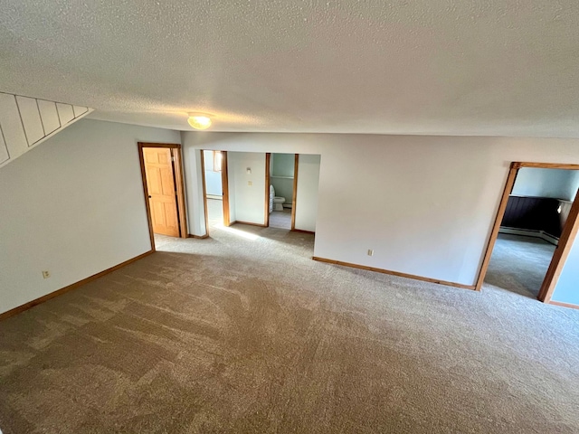 spare room with stairway, a baseboard heating unit, carpet flooring, a textured ceiling, and baseboards