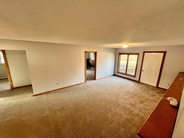 empty room featuring carpet, a textured ceiling, and baseboards