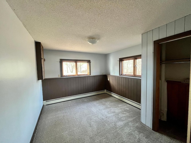 unfurnished bedroom featuring wainscoting, wooden walls, and a textured ceiling