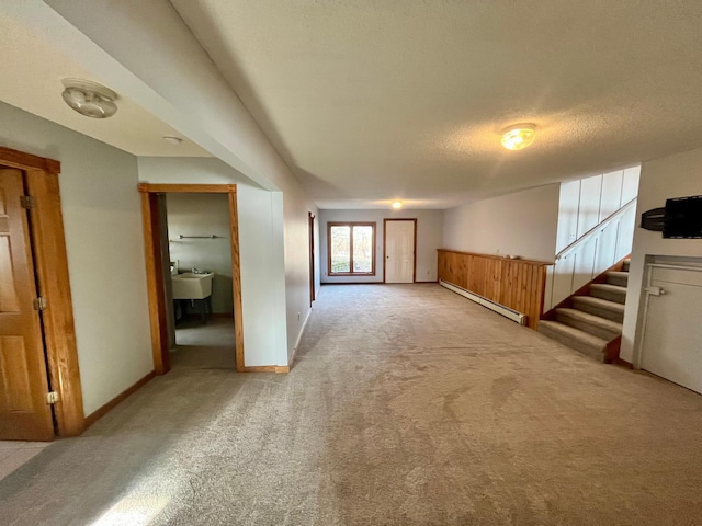 unfurnished room with light colored carpet, stairway, baseboard heating, a sink, and a textured ceiling