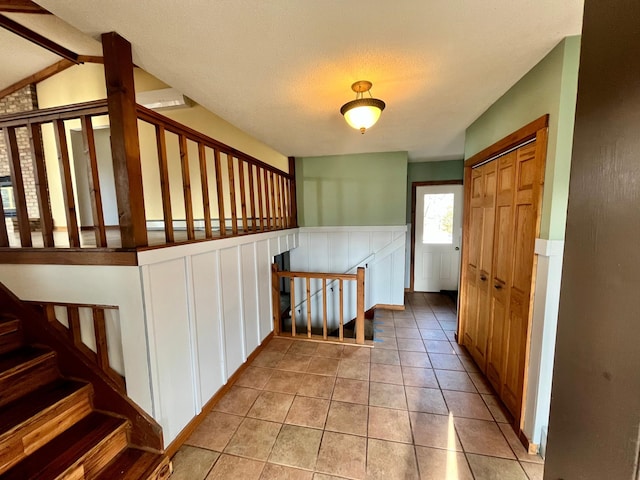 hall featuring light tile patterned floors and wainscoting