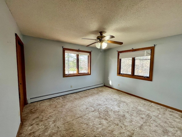 empty room with a textured ceiling, light colored carpet, a ceiling fan, baseboards, and baseboard heating