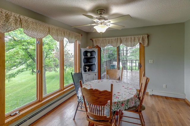 dining area featuring a textured ceiling, a baseboard radiator, baseboards, light wood-style floors, and baseboard heating