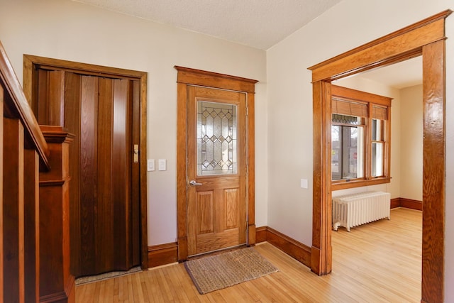 entrance foyer with radiator, light hardwood / wood-style flooring, and a textured ceiling