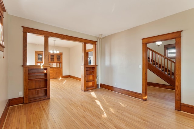 empty room with light hardwood / wood-style floors and a notable chandelier