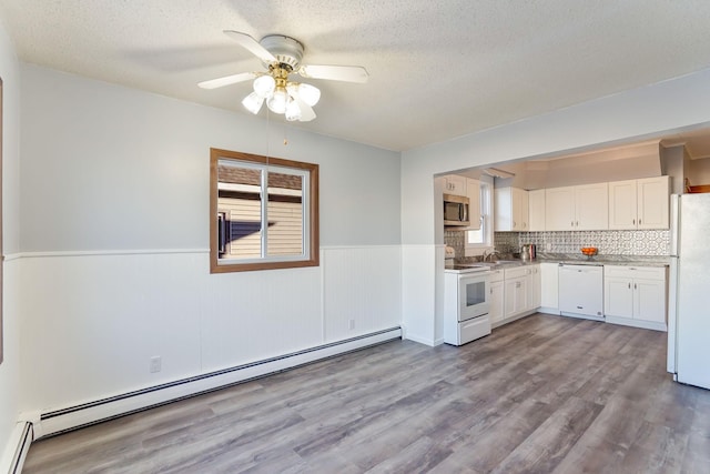 kitchen with sink, a baseboard radiator, light hardwood / wood-style floors, white appliances, and white cabinets