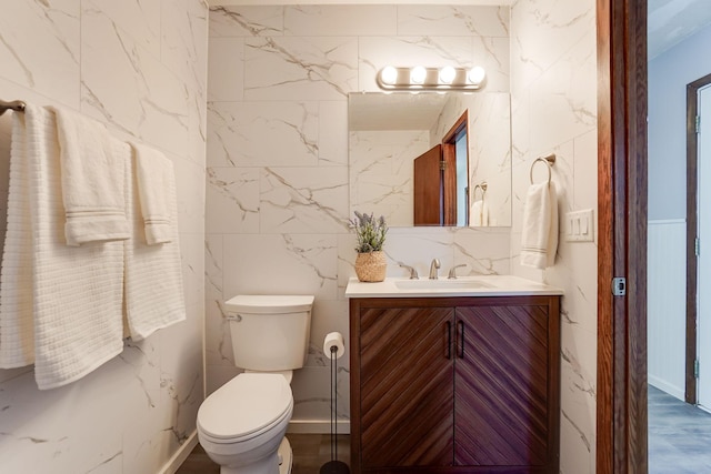 bathroom with vanity, toilet, and tile walls