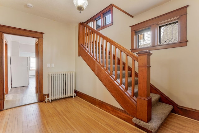 stairs with radiator and hardwood / wood-style flooring