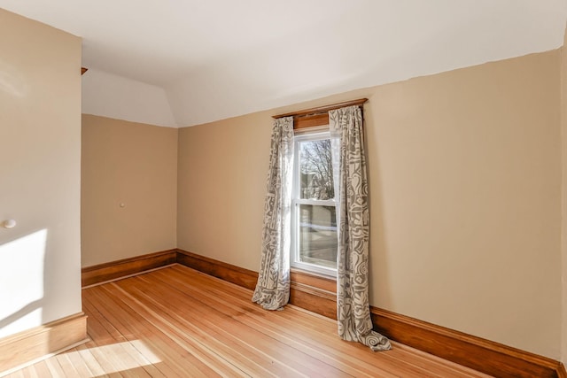 empty room with wood-type flooring and vaulted ceiling