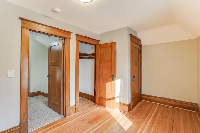 unfurnished bedroom with vaulted ceiling, light wood-type flooring, and a closet