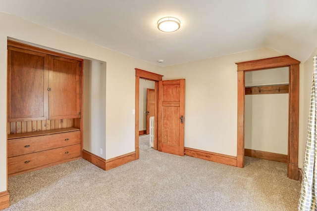 unfurnished bedroom with a closet, light colored carpet, and lofted ceiling