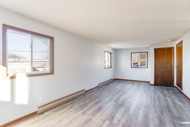 unfurnished room with light wood-type flooring, a textured ceiling, and a baseboard radiator