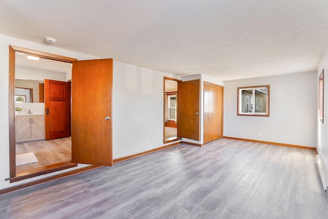 unfurnished room featuring sink, light hardwood / wood-style floors, and a textured ceiling