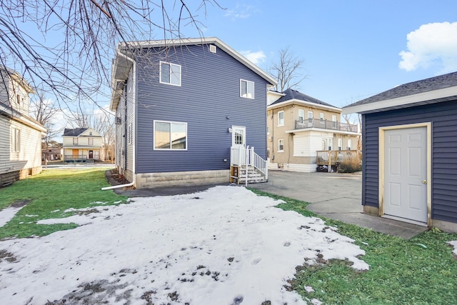 snow covered rear of property featuring a yard