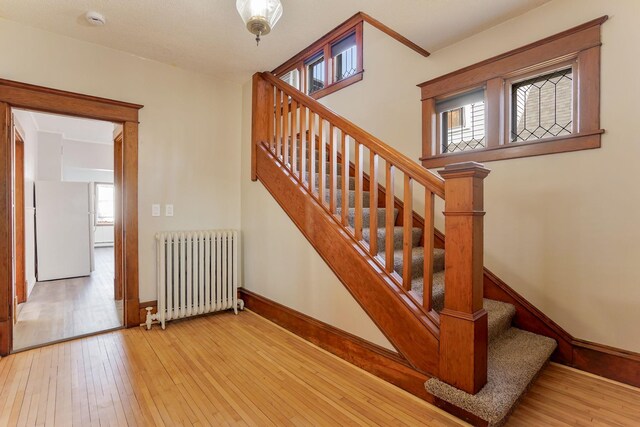 409 Adams St, Arlington, MN 55307 - staircase featuring radiator heating unit, wood-type flooring, and baseboards