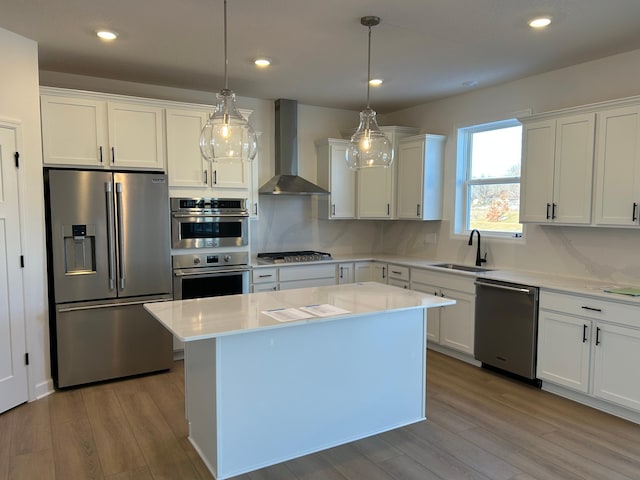 kitchen featuring decorative light fixtures, sink, appliances with stainless steel finishes, and wall chimney exhaust hood