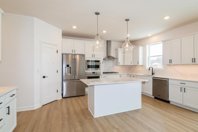 kitchen featuring a kitchen island, pendant lighting, sink, stainless steel appliances, and wall chimney exhaust hood