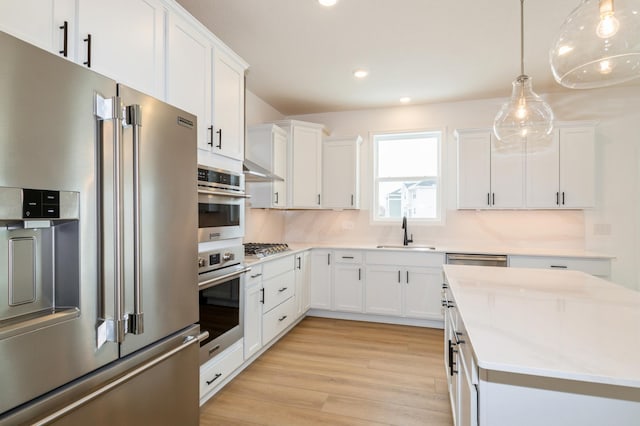 kitchen with stainless steel appliances, white cabinetry, sink, and pendant lighting