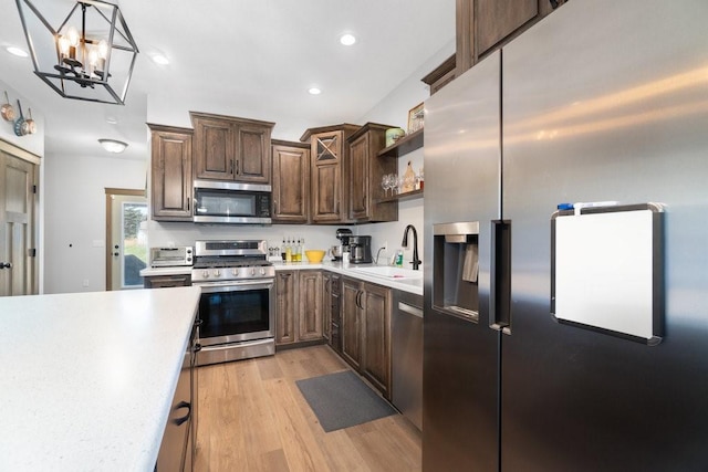 kitchen featuring hanging light fixtures, sink, light hardwood / wood-style flooring, appliances with stainless steel finishes, and a notable chandelier