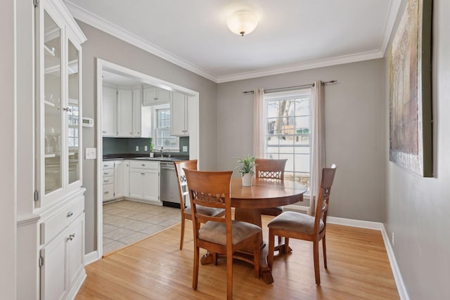 dining area featuring crown molding, sink, and light wood-type flooring