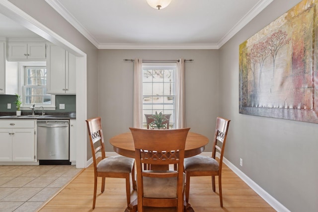 dining room featuring light hardwood / wood-style flooring, sink, crown molding, and a wealth of natural light