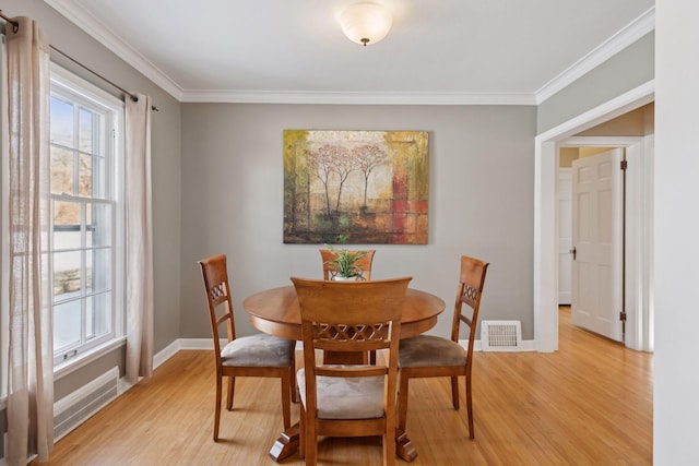 dining space with ornamental molding and light wood-type flooring