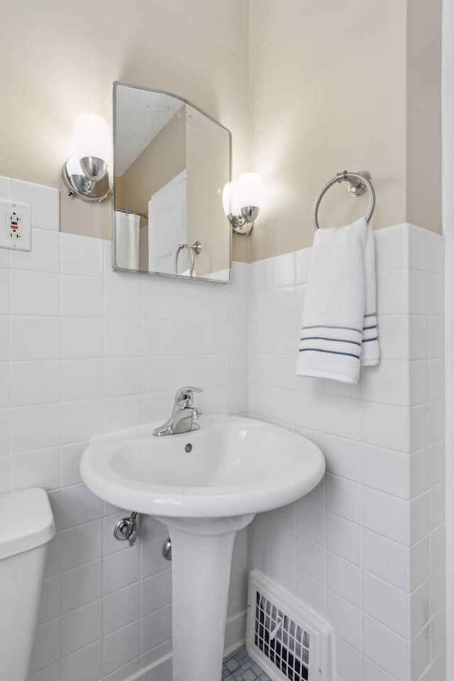 bathroom with tile walls and toilet