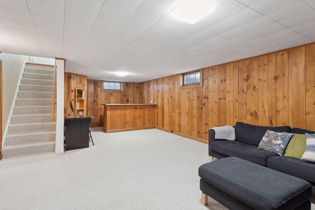 carpeted living room with wood walls